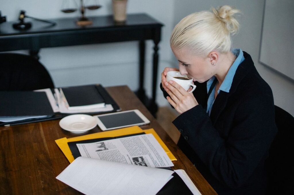 Femme buvant du café à un bureau avec des documents