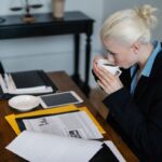 Femme buvant du café à un bureau avec des documents