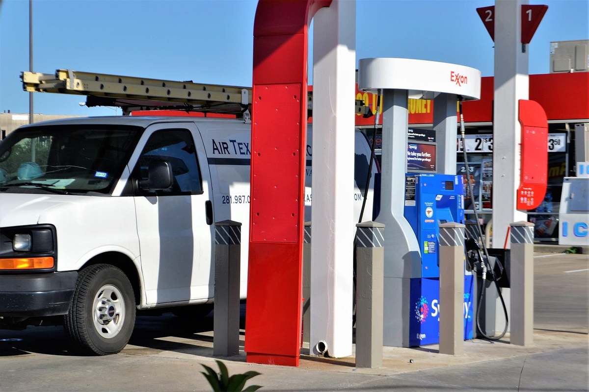 Camion blanc stationné près de pompes à carburant à une station-service sous un ciel bleu