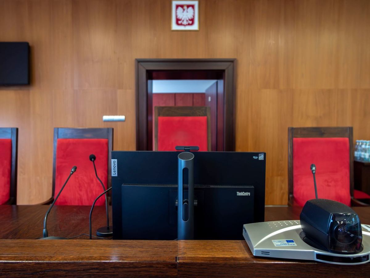 Salle de réunion avec écran, chaises rouges, microphones et projecteur
