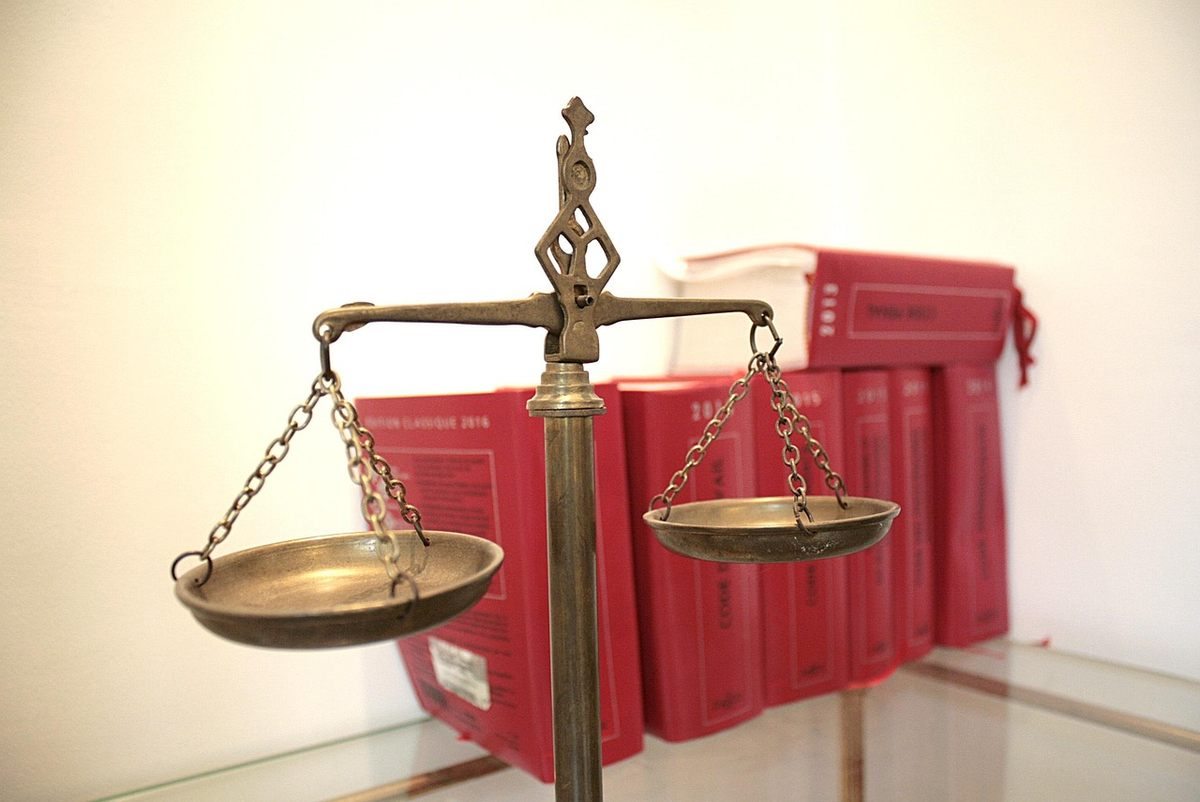 Balance de justice en bronze sur une table devant des livres rouges reliés