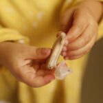 Un enfant tient un appareil auditif et son petit embout en main