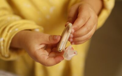Un enfant tient un appareil auditif et son petit embout en main