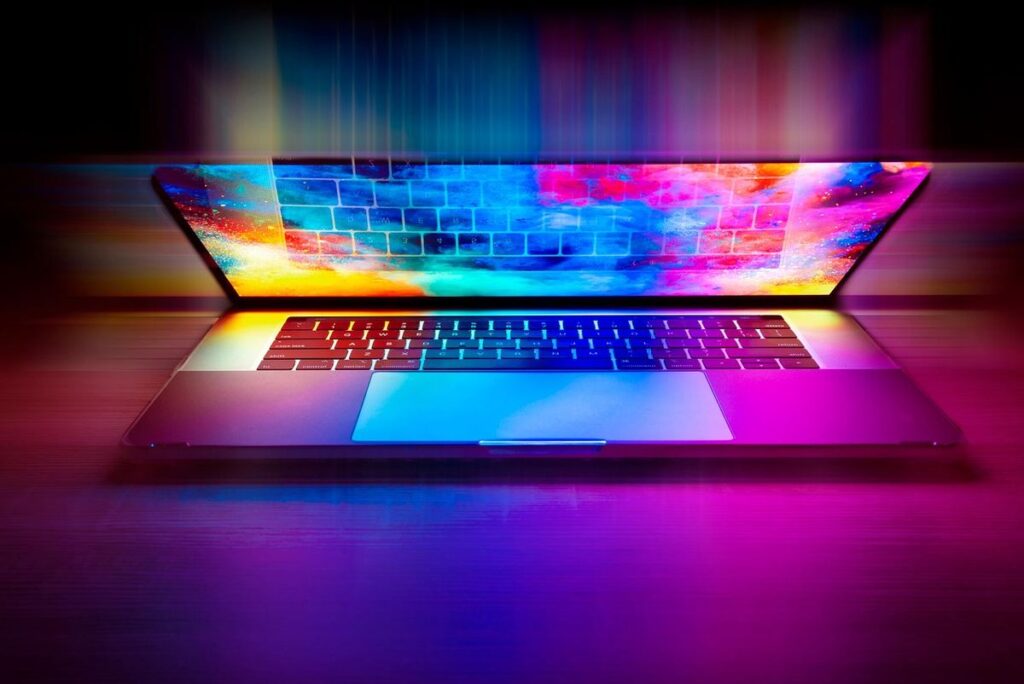 Un ordinateur portable ouvert projette des couleurs vives sur le clavier