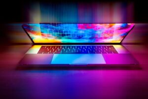 Un ordinateur portable ouvert projette des couleurs vives sur le clavier