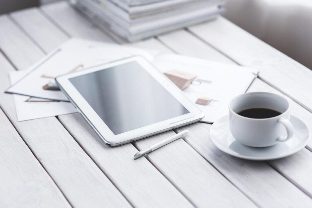 Tablette blanche, stylus, tasse de café sur saucer, documents sur table blanche