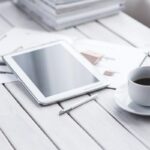 Tablette blanche, stylus, tasse de café sur saucer, documents sur table blanche