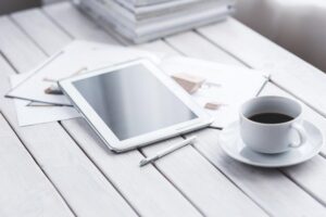 Tablette blanche, stylus, tasse de café sur saucer, documents sur table blanche