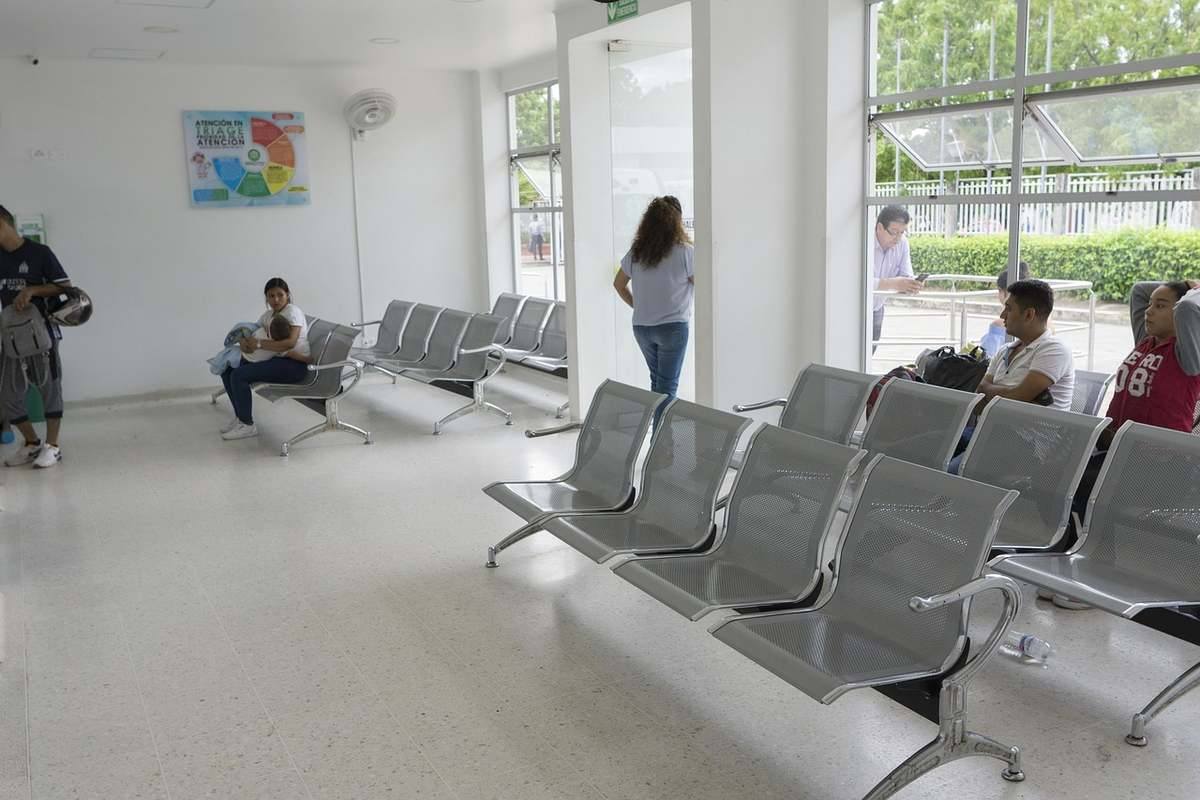 Salle d'attente avec chaises métalliques et personnes en attente Salle d'attente avec chaises métalliques et personnes en attente